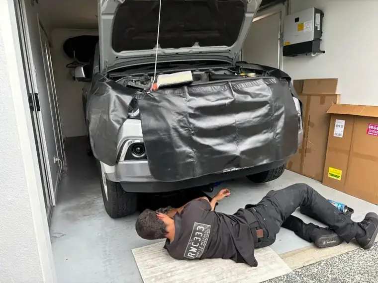Licensed inspector checking under a car during a mobile RWC